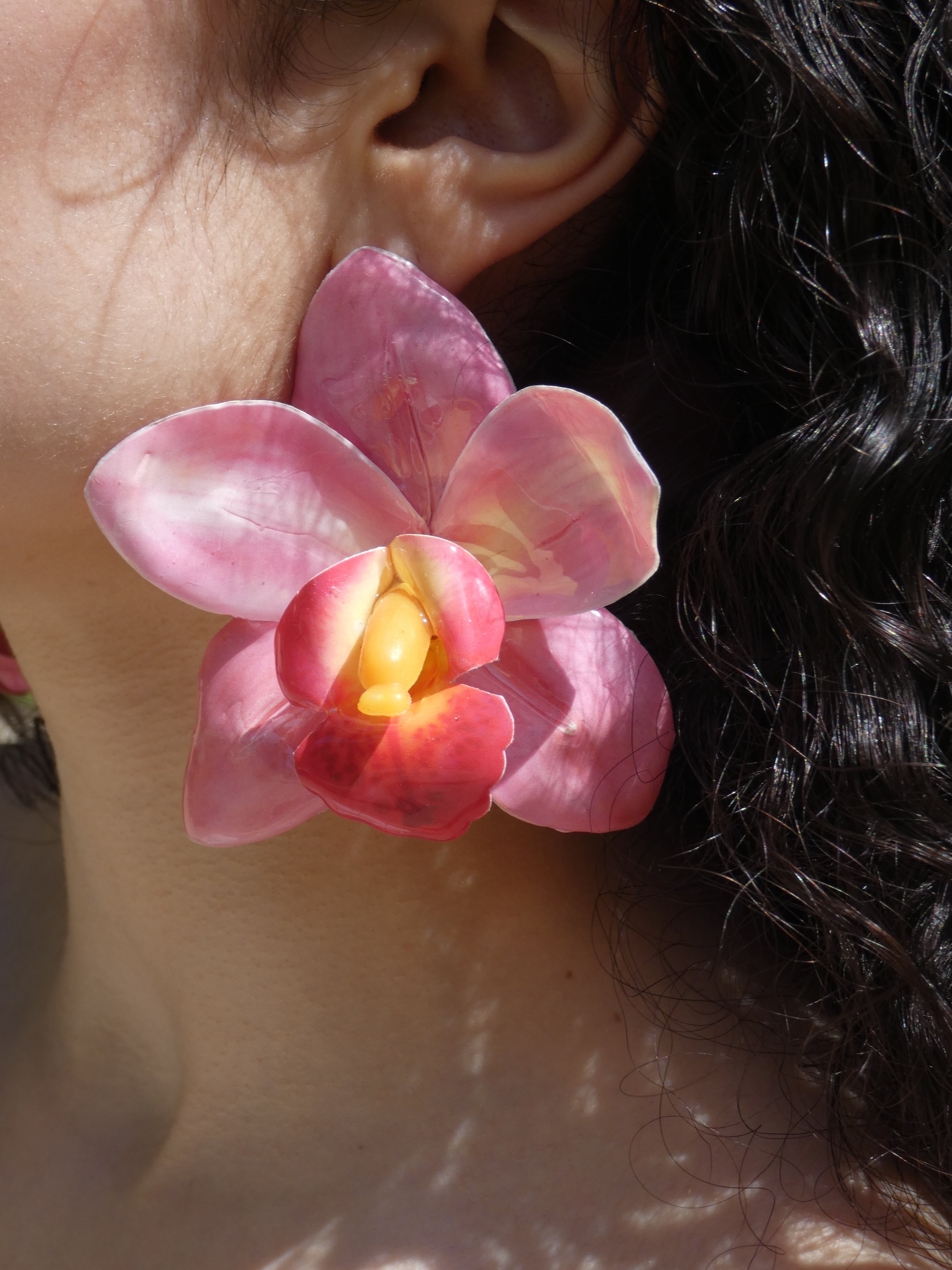 Boucle d’oreille orchidée rose et fuchsia avec cœur jaune doré portée par un modèle