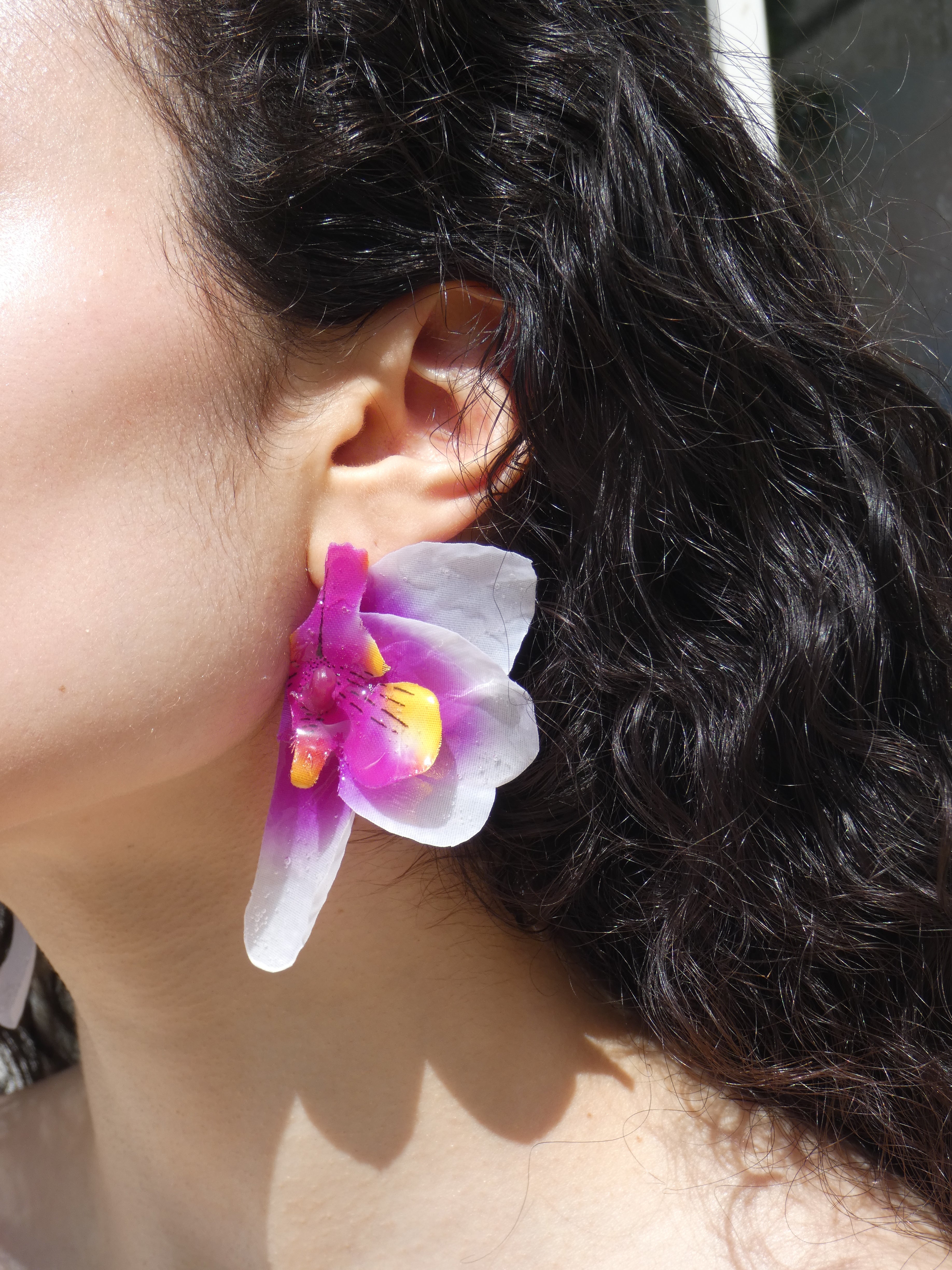 Boucle d’oreille orchidée violet intense et blanc nacré portée par un modèle