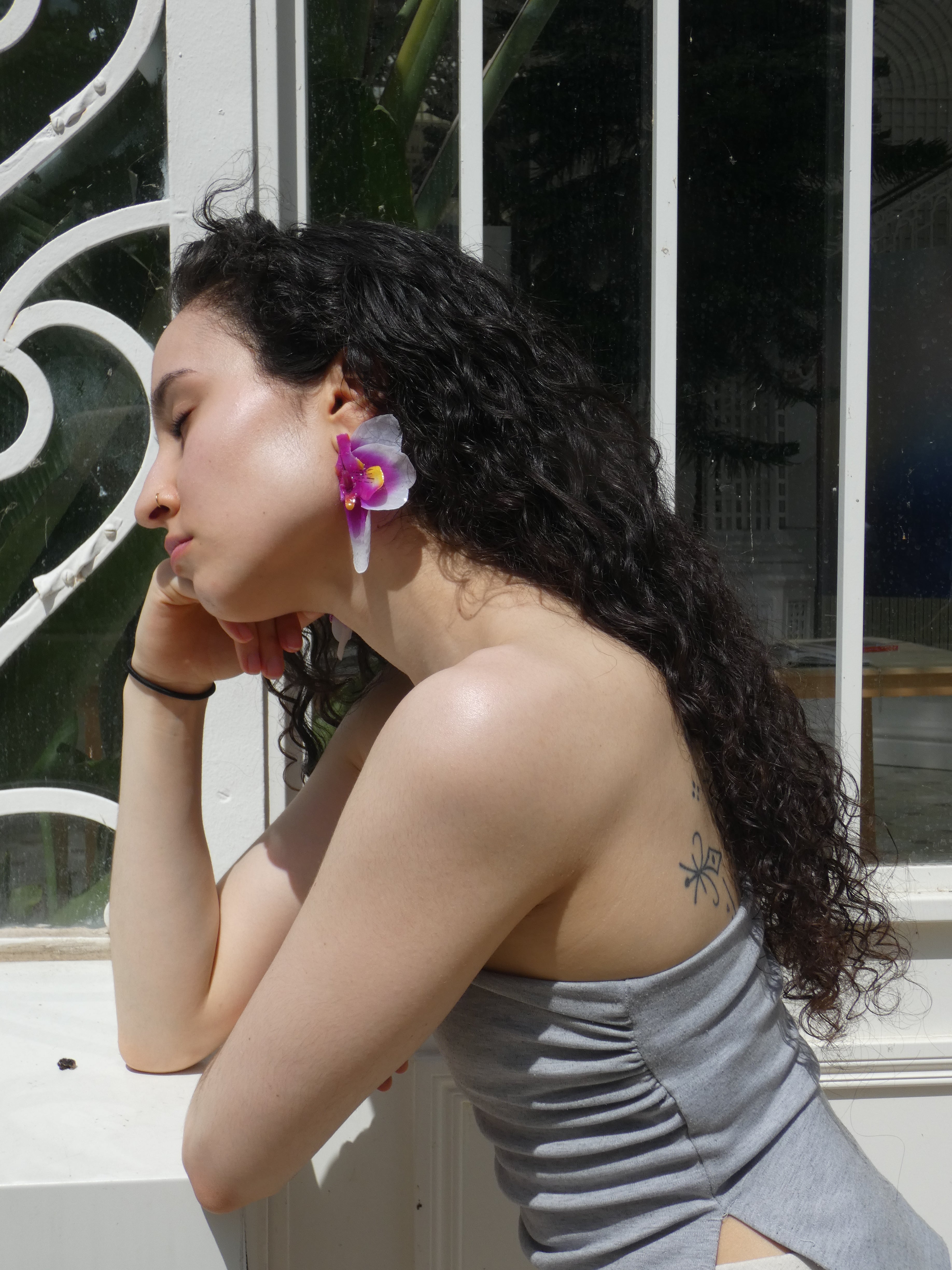 Boucle d’oreille orchidée violette portée en lumière naturelle