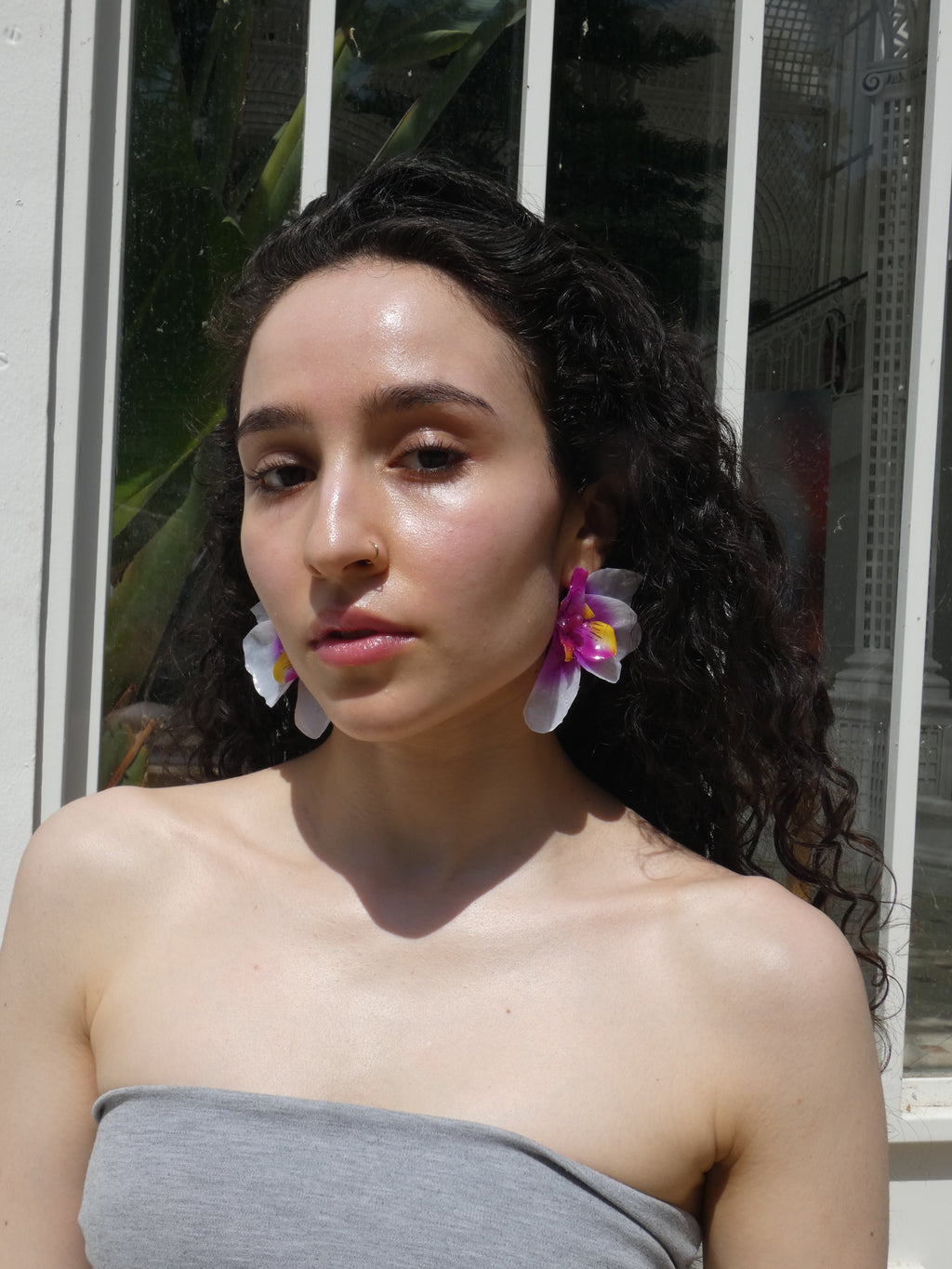 Boucle d’oreille orchidée violette avec détails jaunes et nacre portée en lumière naturelle