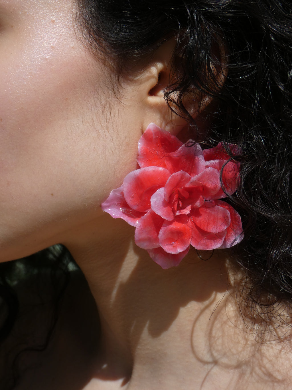 Grande boucle d’oreille fleur rouge corail artisanale portée par un modèle