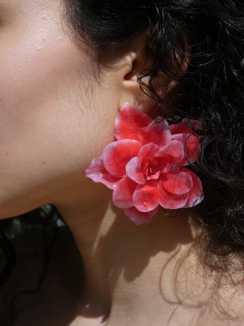 Grande boucle d’oreille fleur rouge corail artisanale portée par un modèle