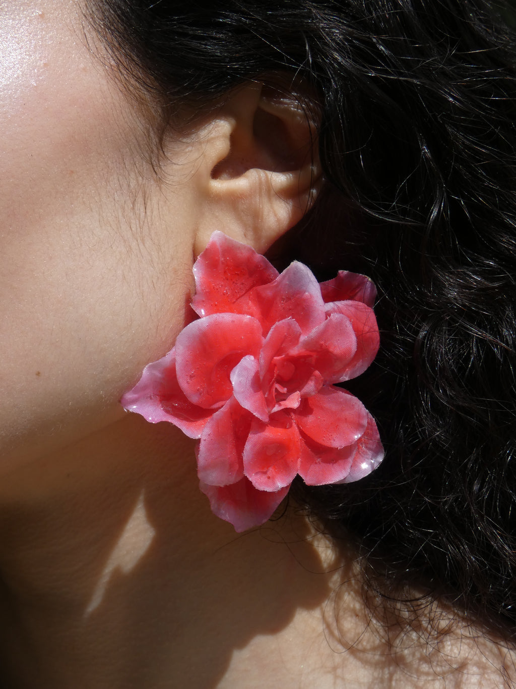Boucle d’oreille florale rouge corail vue de profil sur un modèle