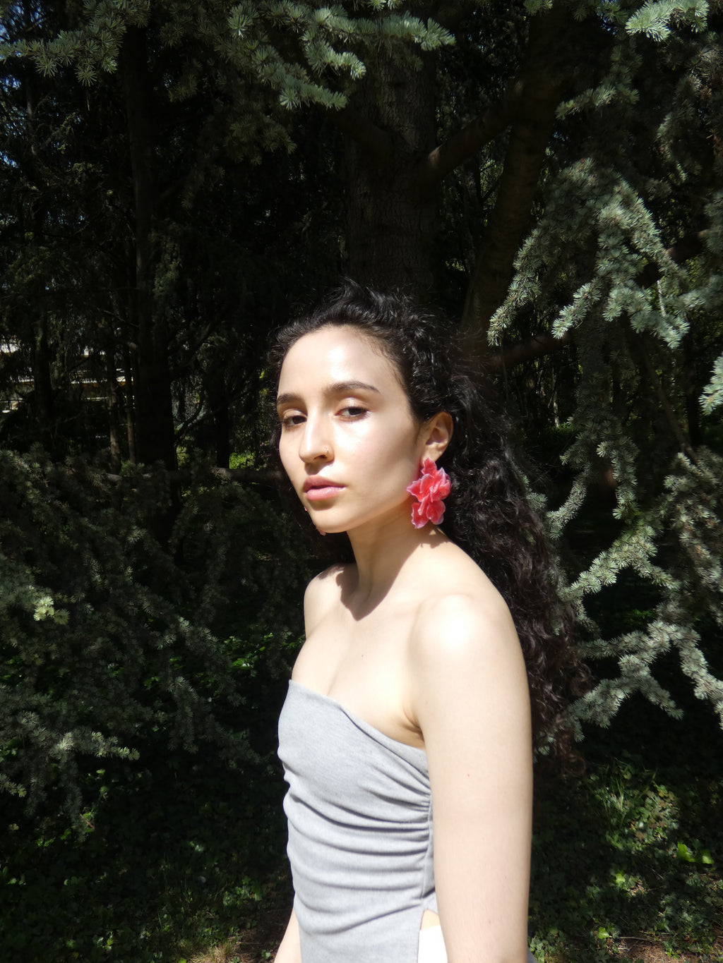 Boucle d’oreille fleur rouge aux pétales superposés portée en extérieur