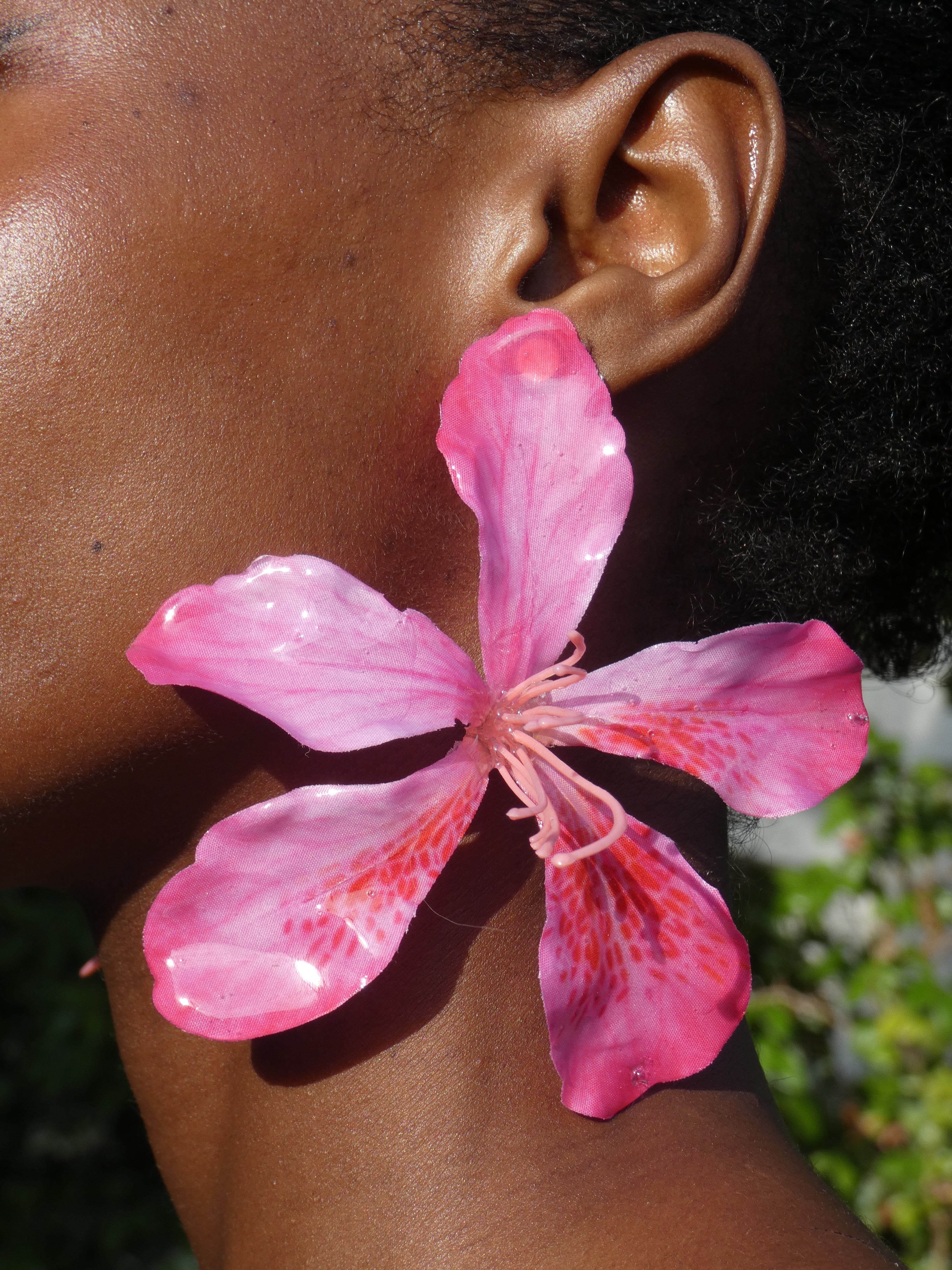 Grande boucle d’oreille fleur rose fuchsia artisanale portée par un modèle