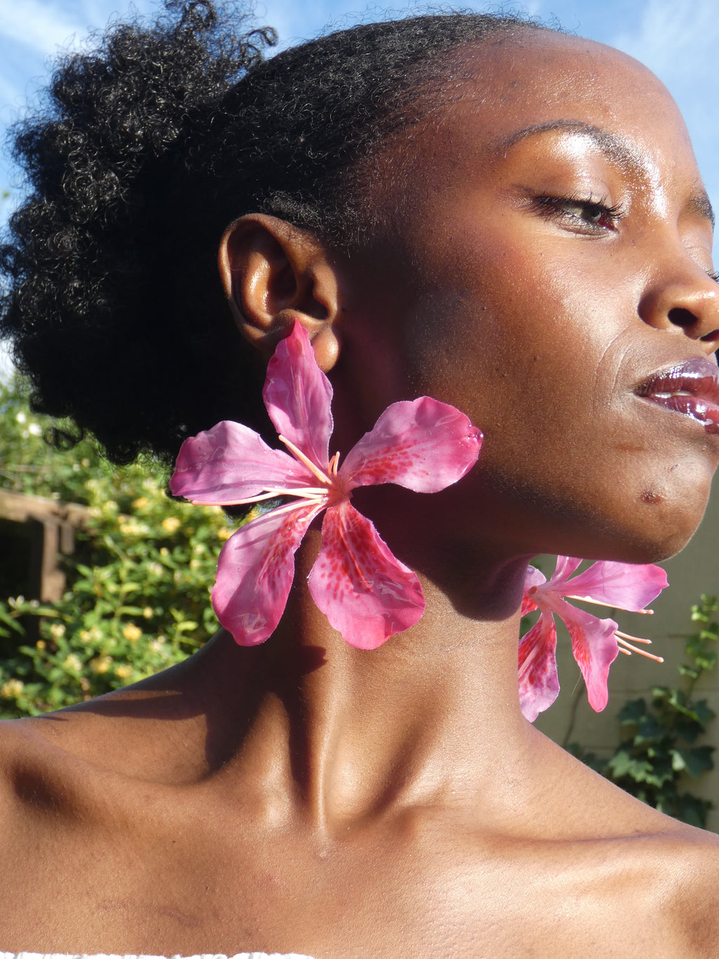 Grande boucle d’oreille fleur rose fuchsia aux nuances de rose intense portée en extérieur