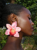 Grande boucle d’oreille orchidée rose pastel aux détails pêche portée par un modèle