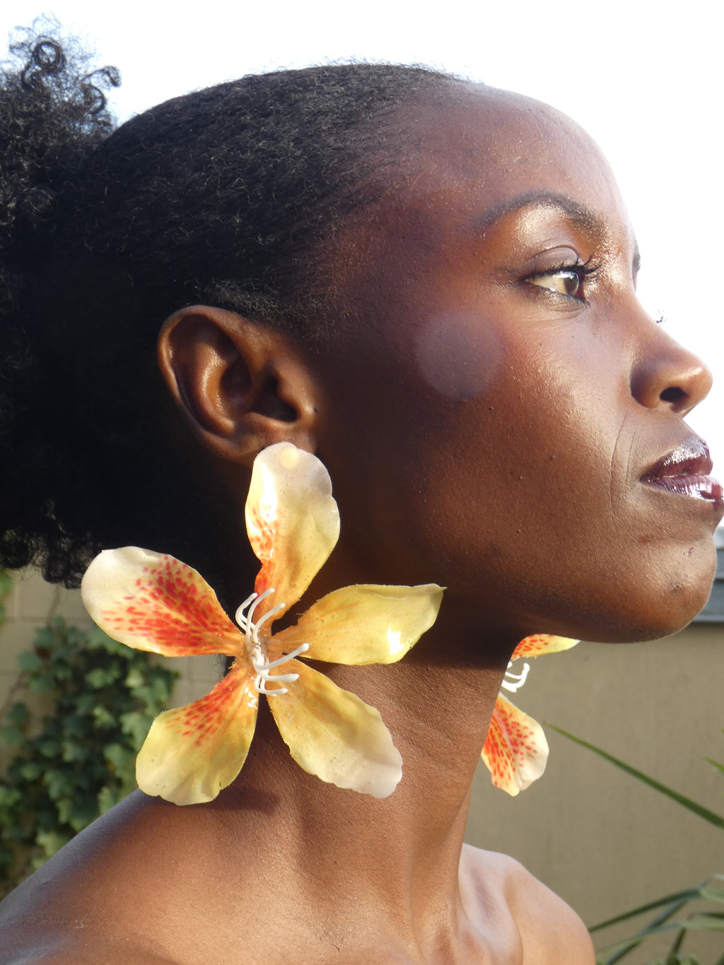 Boucle d'oreille florale jaune et orange inspirée des fleurs tropicales portée de profil