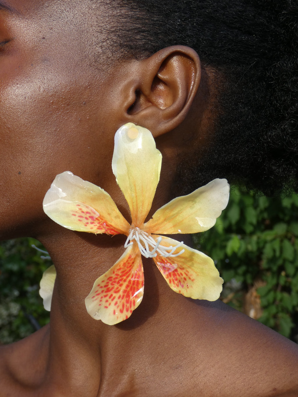 Grande boucle d'oreille fleur jaune tachetée d'orange artisanale portée par un modèle