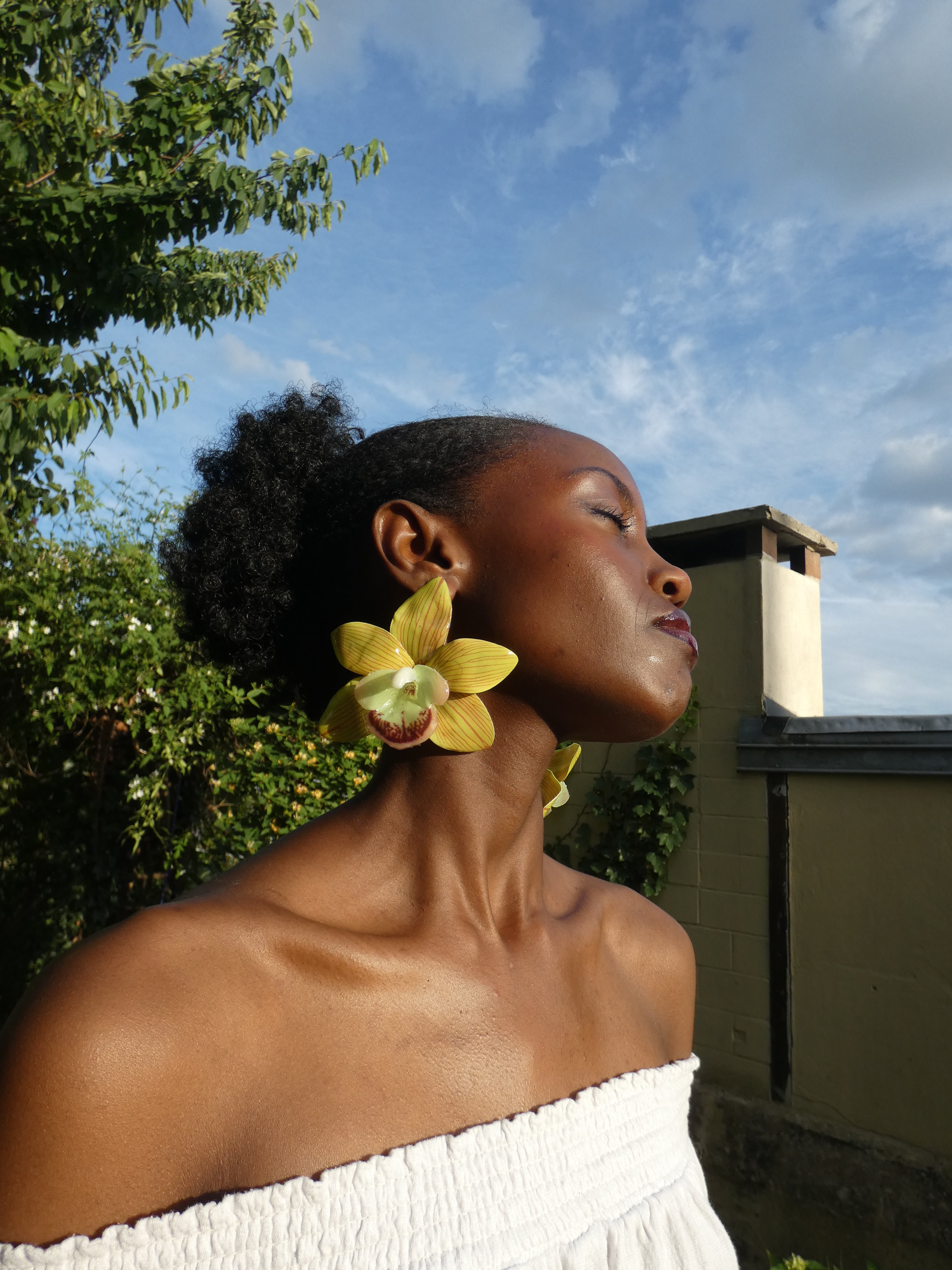 Grande boucle d'oreille florale verte artisanale portée en extérieur 