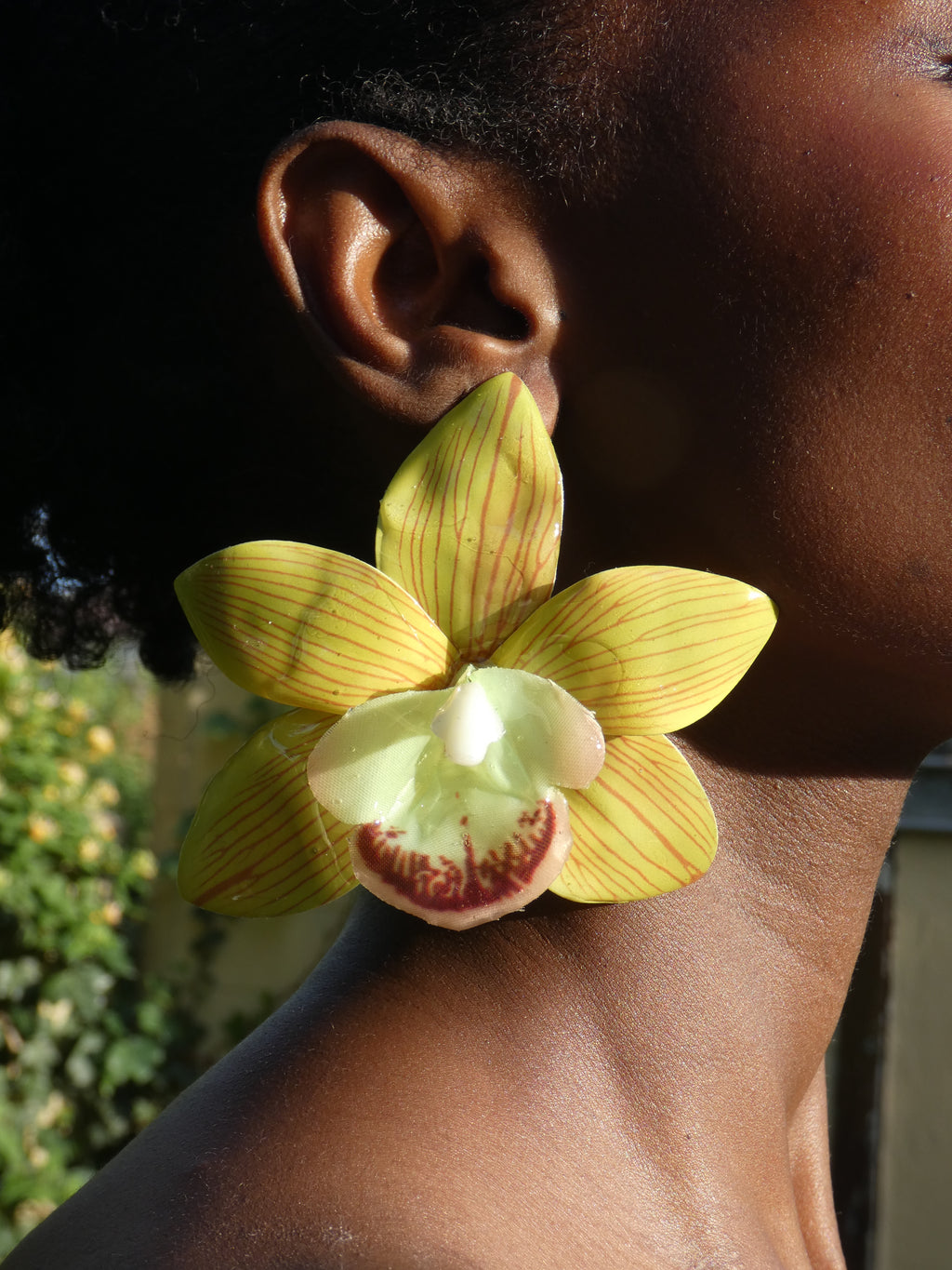 Détail d'une boucle d'oreille orchidée vert chartreuse portée à l'oreille