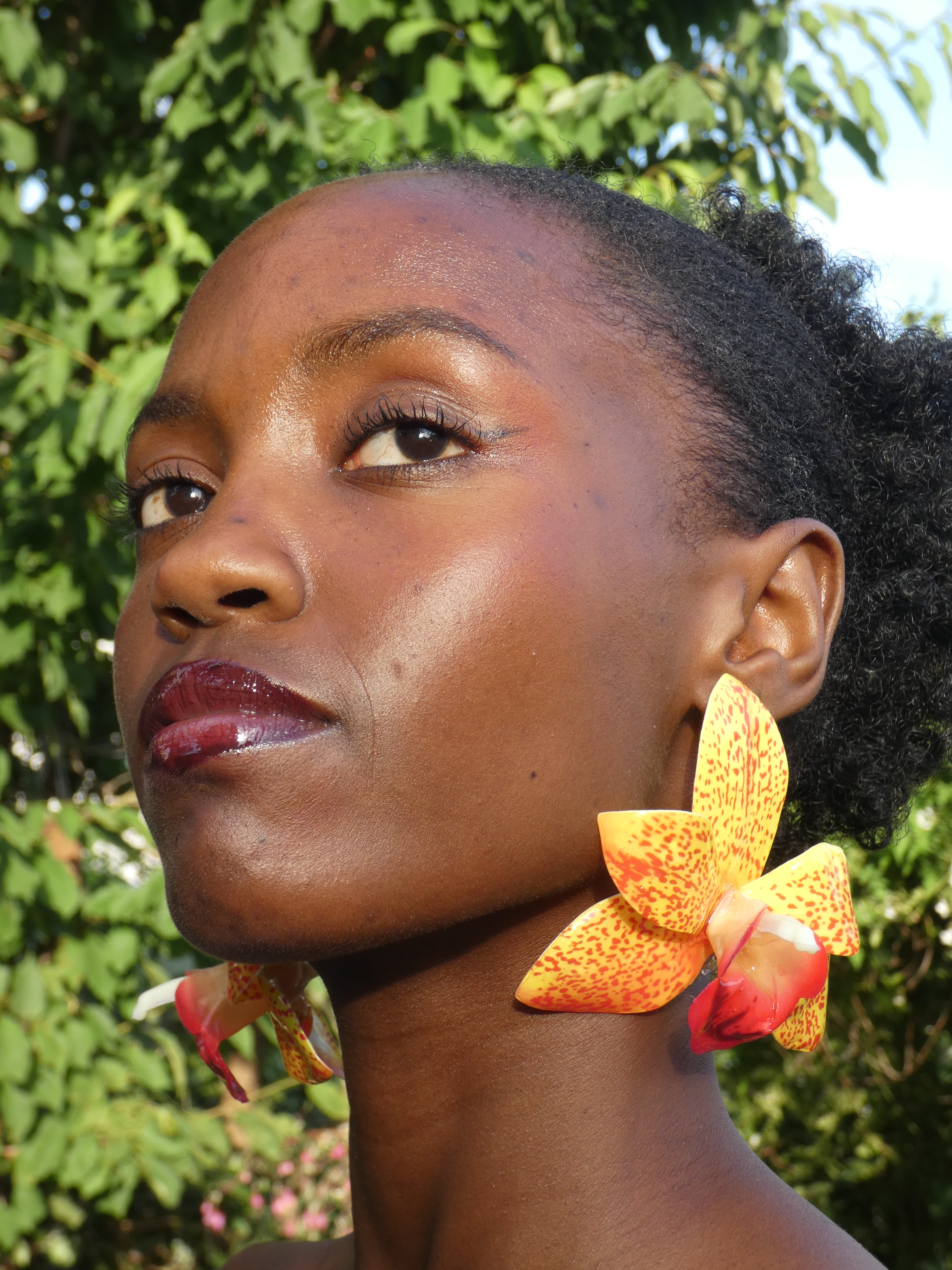 Grande boucle d'oreille florale jaune et orange artisanale portée à l'oreille