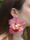 Grande boucle d'oreille orchidée rose artisanale portée par un modèle
