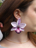 Grande boucle d'oreille orchidée Phalaenopsis violette et blanche artisanale portée par un modèle