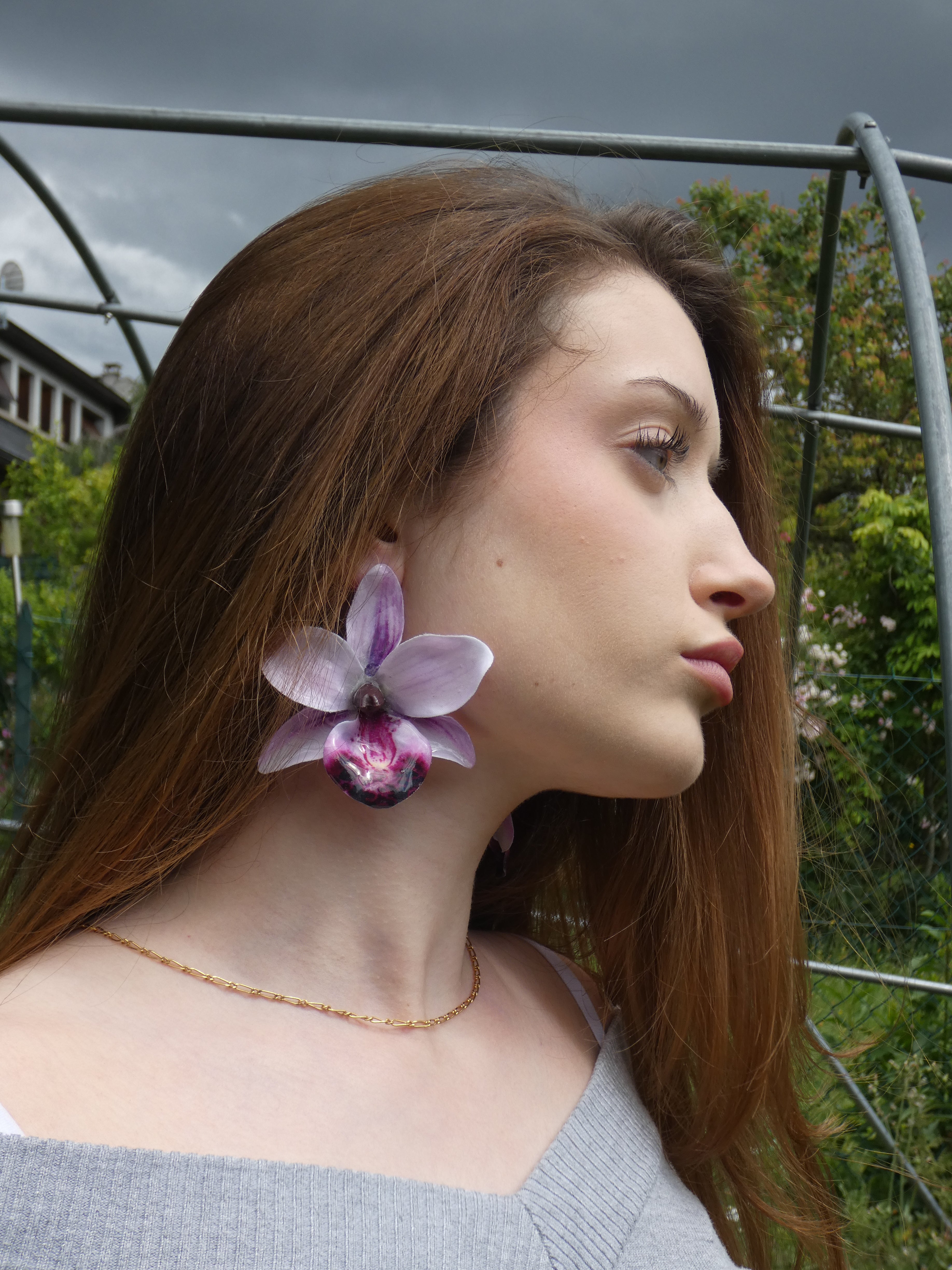 Grande boucle d'oreille orchidée aux nuances de lilas, lavande et violet portée par un modèle