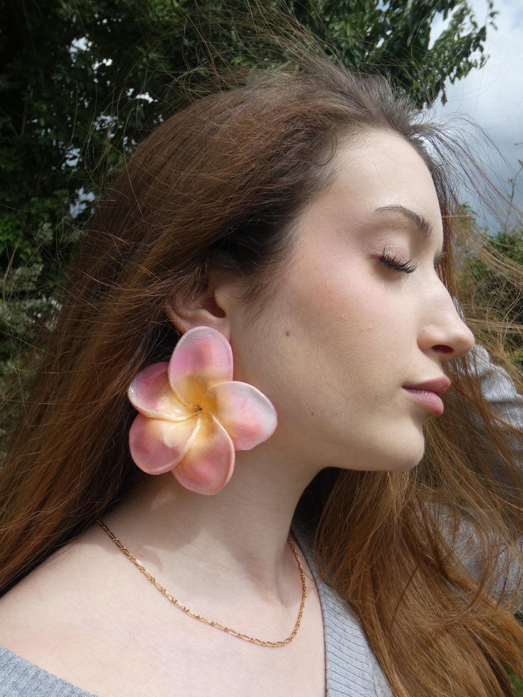 Boucle d'oreille fleur plumeria tropicale rose pastel porté par un modèle
