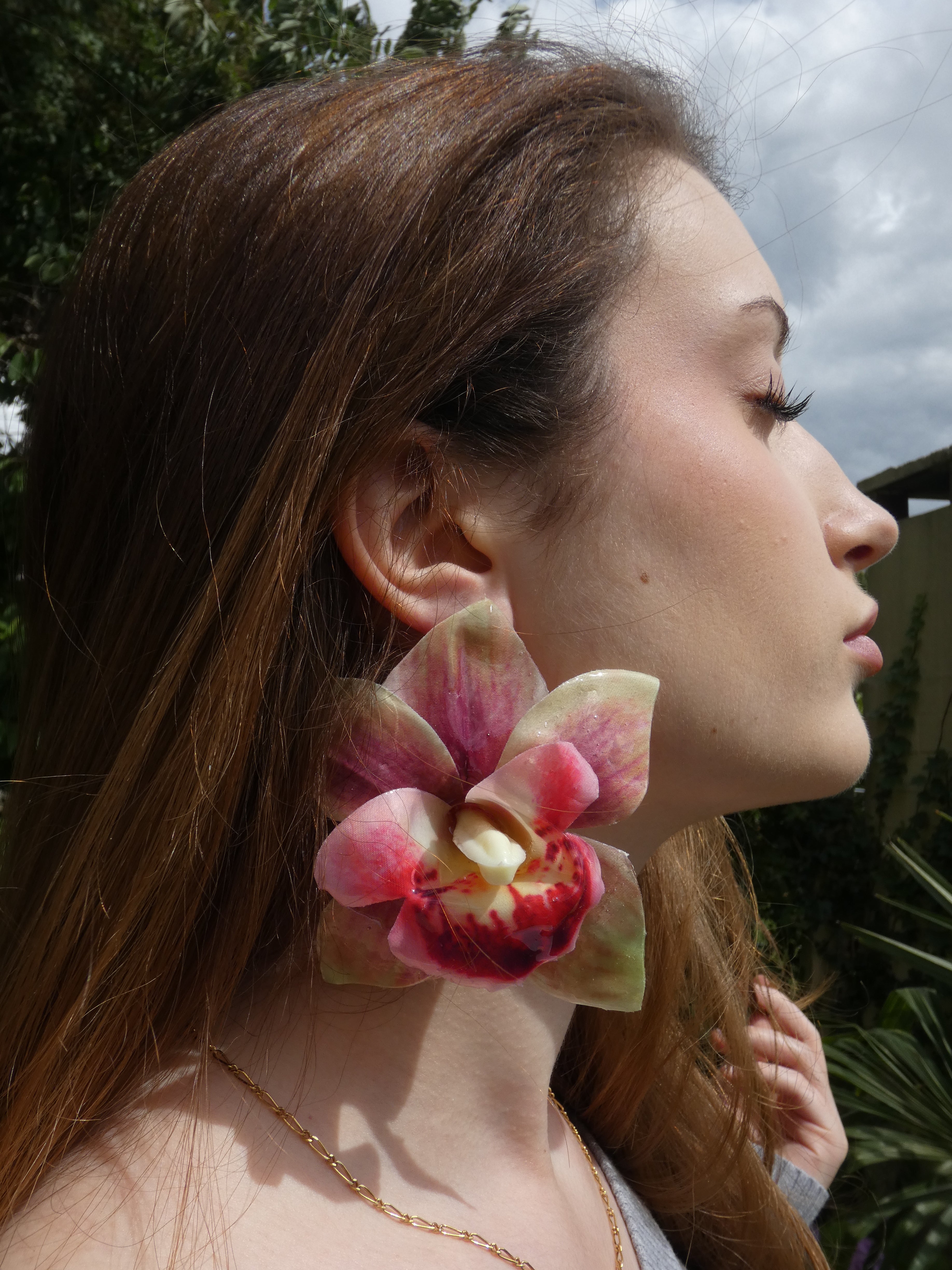 boucle d'oreille fleur orchidée rose verte artisanales en tissu peint et résine portées par un modèle