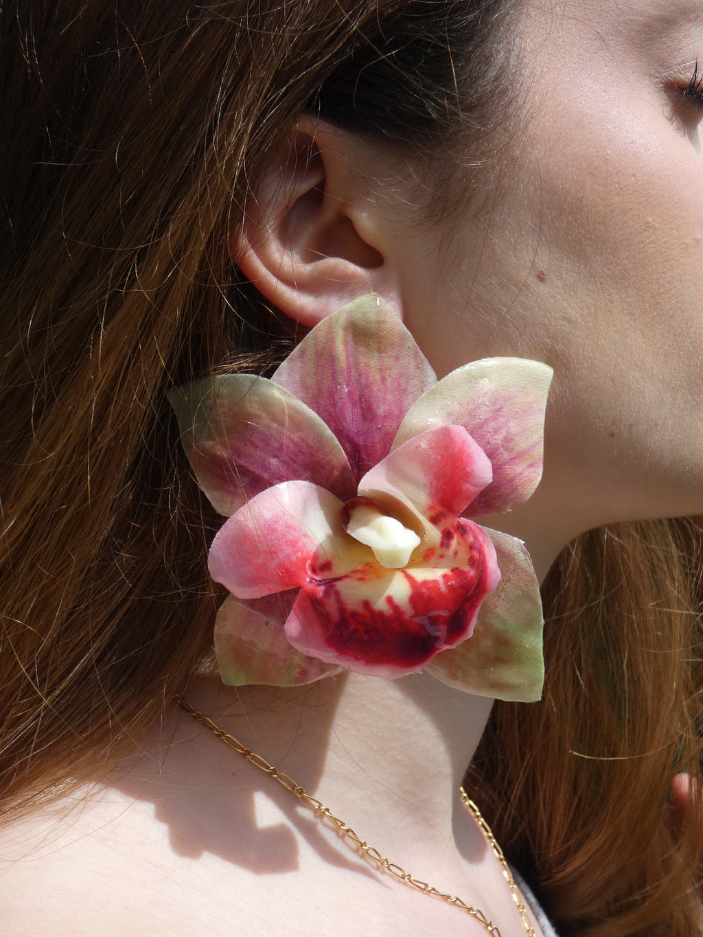 grande boucle d'oreille fleur orchidée rose et verte faite main en tissu et résine portée à l'oreille