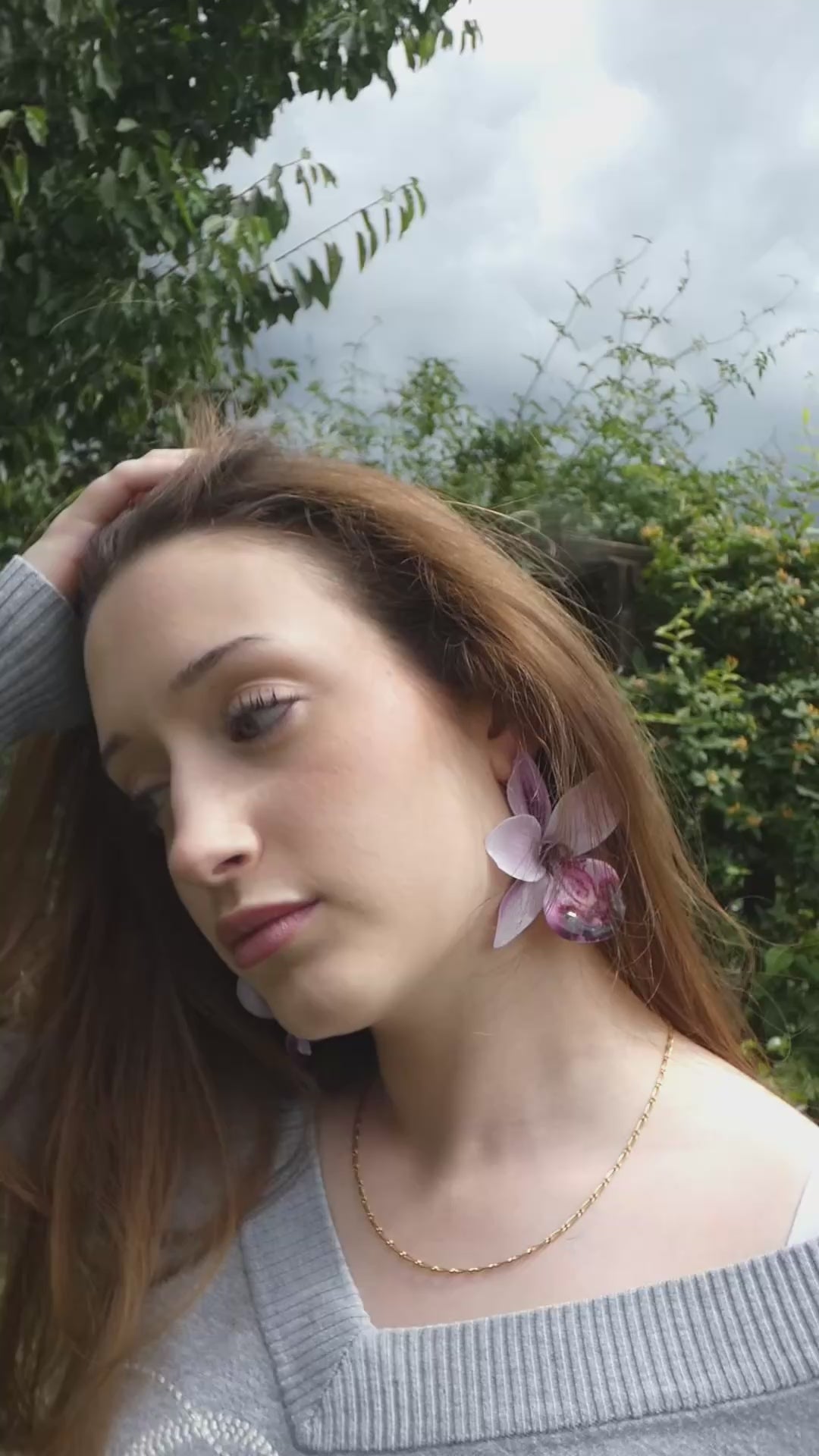 Vidéo présentant une grande boucle d'oreille orchidée aux nuances de lilas, lavande et violet profond portée de profil