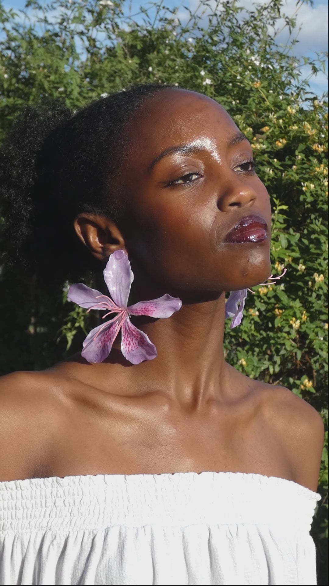 Vidéo montrant le mouvement et les détails d’une grande boucle d’oreille fleur rose lilas artisanale portée par un modèle
