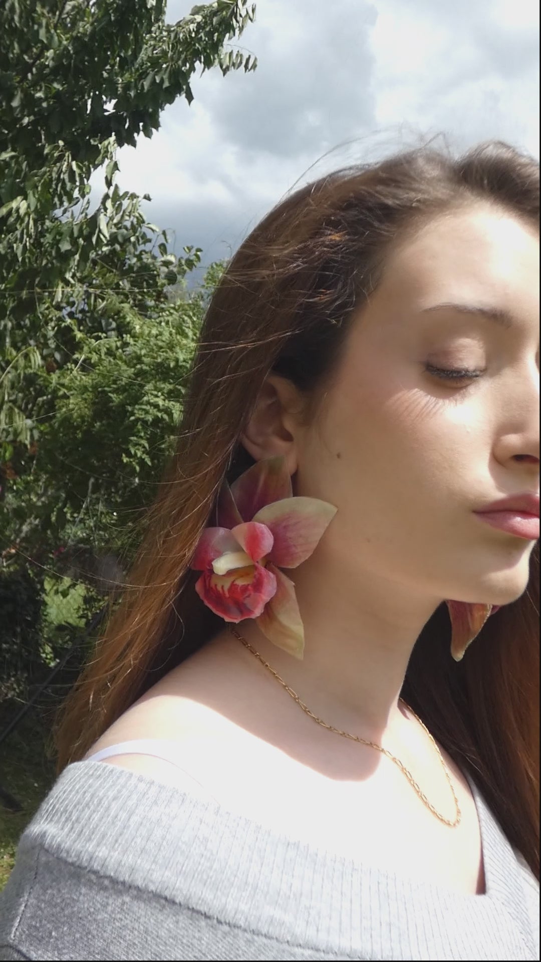 vidéo d'une grande paire de boucle d'oreille fleur orchidée verte et rose artisanale portée par un modèle
