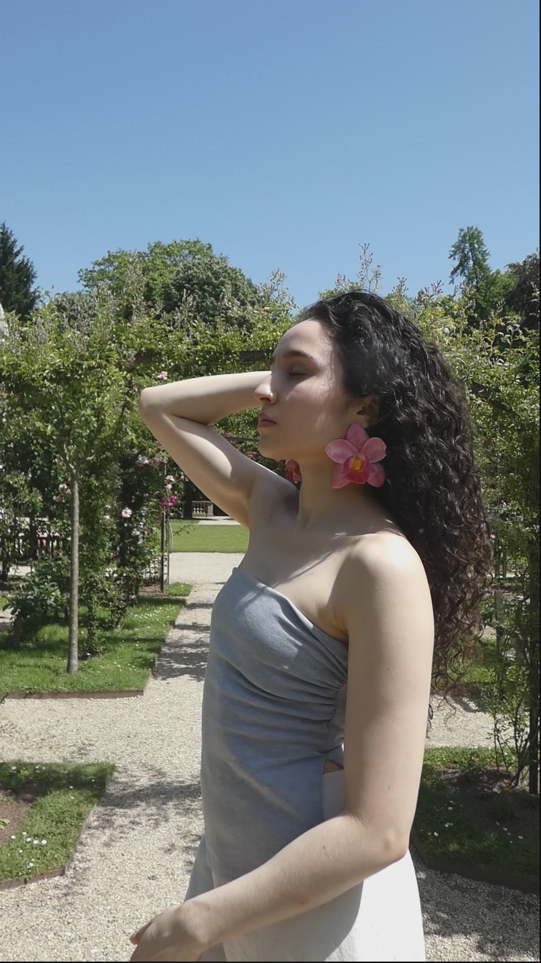 Vidéo montrant les détails et le mouvement d’une boucle d’oreille orchidée rose fuchsia portée par un modèle
