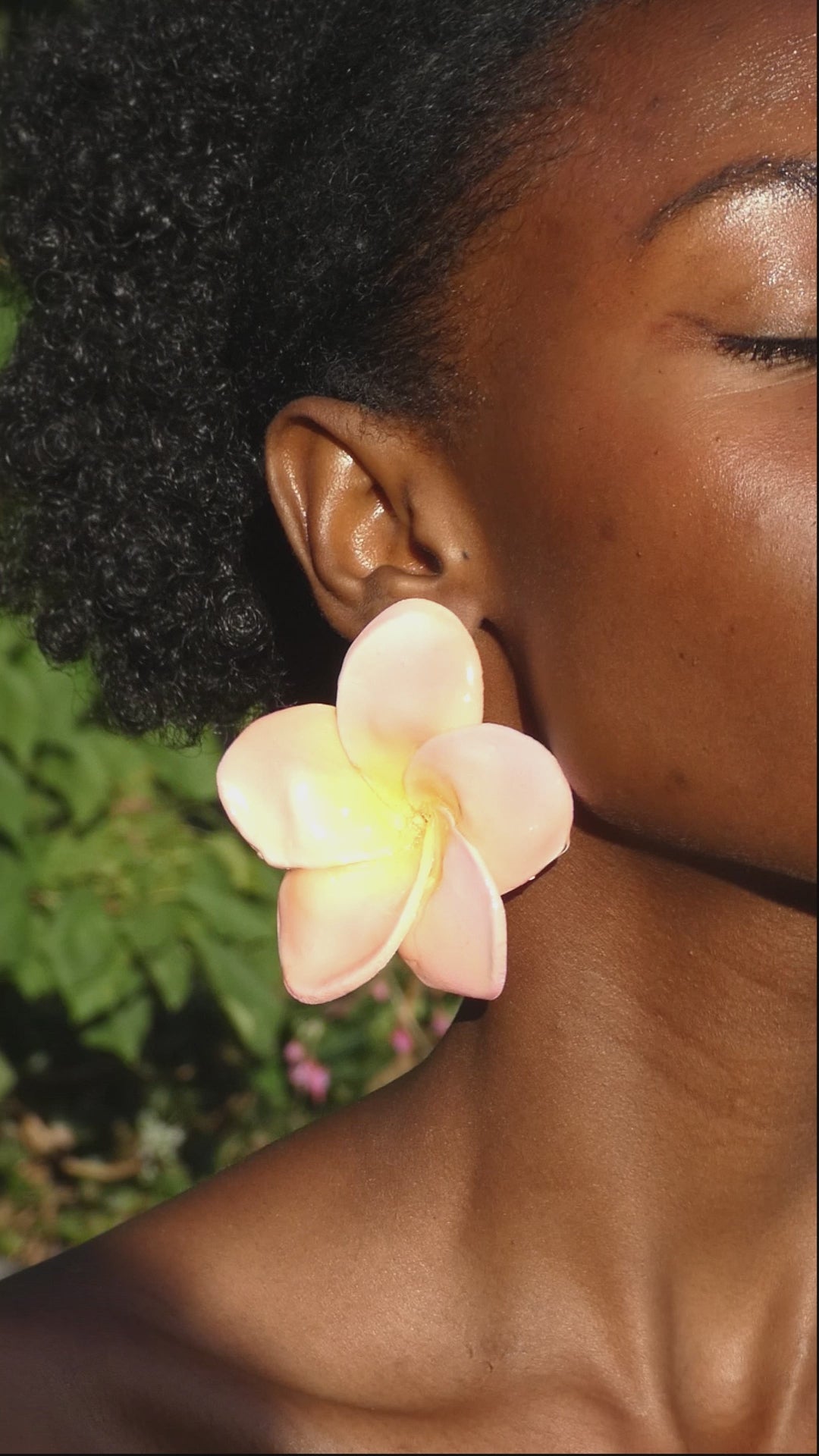 vidéo montrant une paire de boucle d'oreille fleur plumeria artisanale légère portée en mouvement